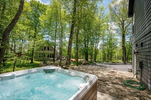 Un bain à remous situé dans un espace boisé, avec une maison en arrière-plan.