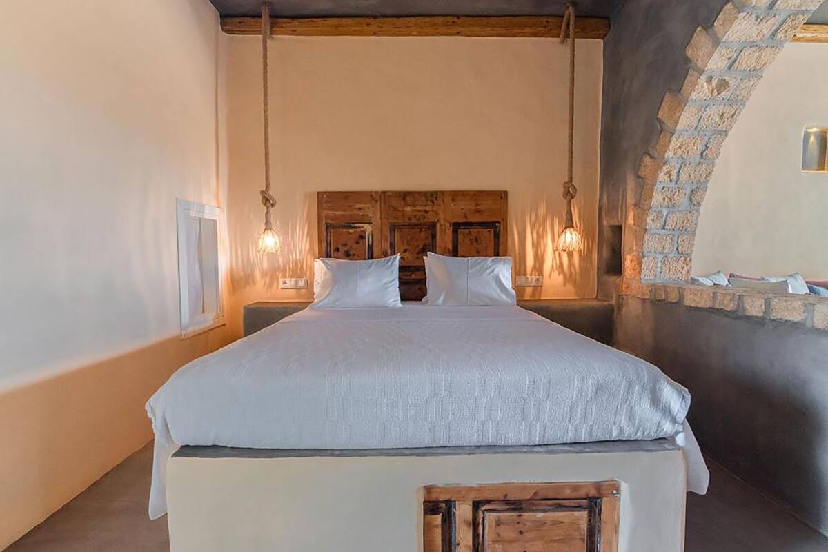 A bedroom with a large bed, wooden headboard, and hanging light fixtures.