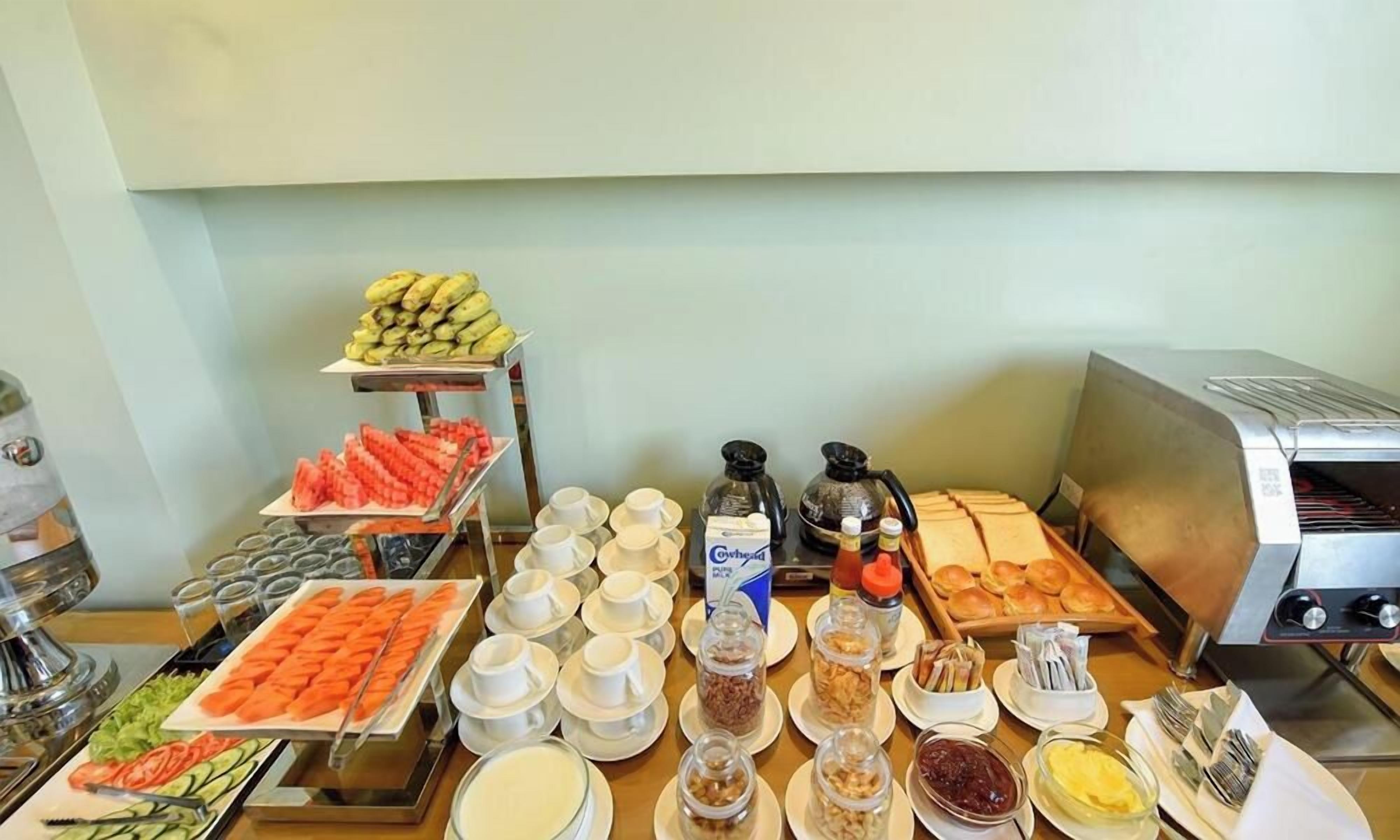 A buffet with various food items and beverages, including fruits, vegetables, and hot beverages.