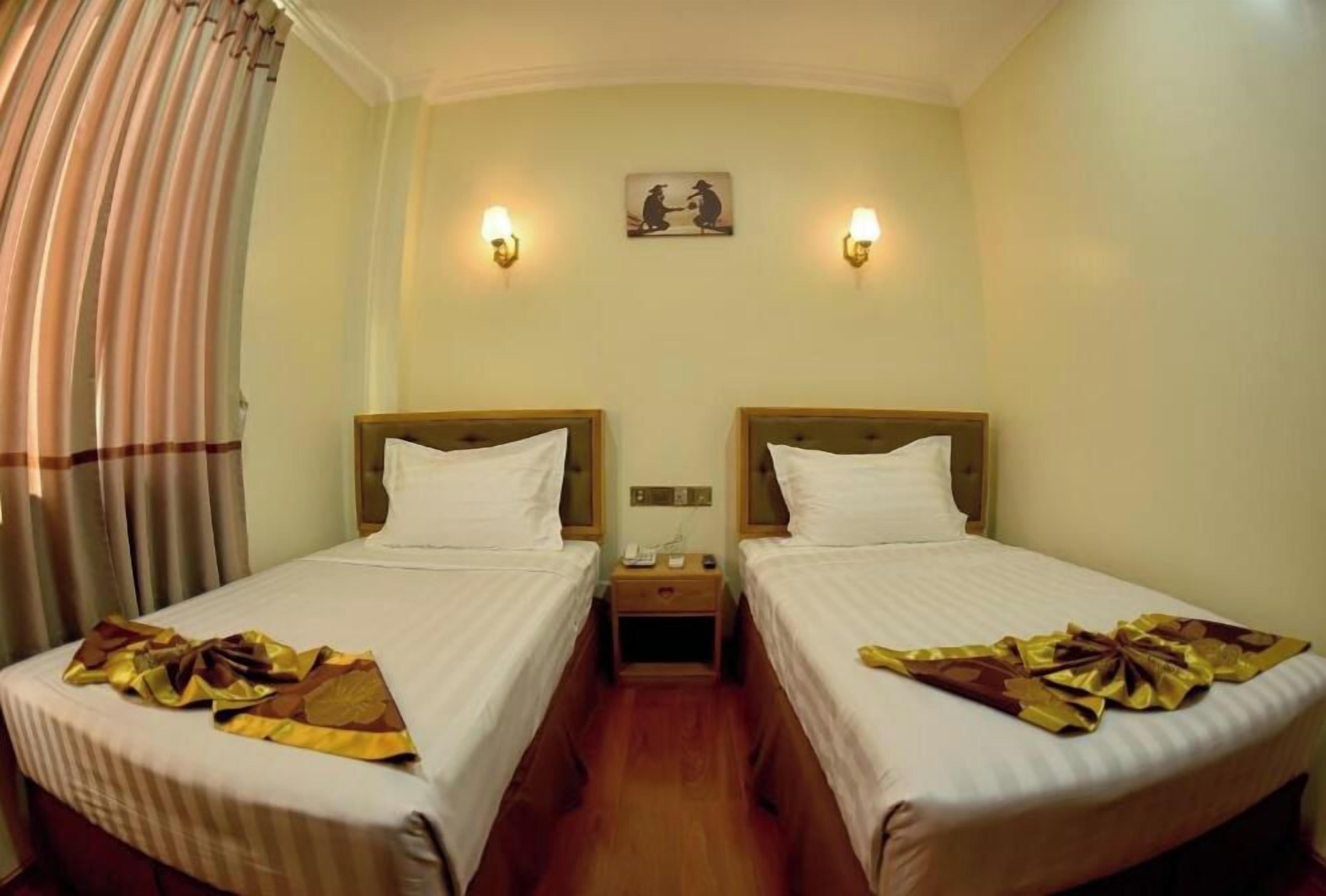 A hotel room with two beds, a nightstand, a wall-mounted painting, and a curtain.