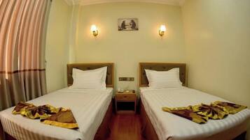 A hotel room with two beds, a nightstand, a wall-mounted painting, and a curtain.