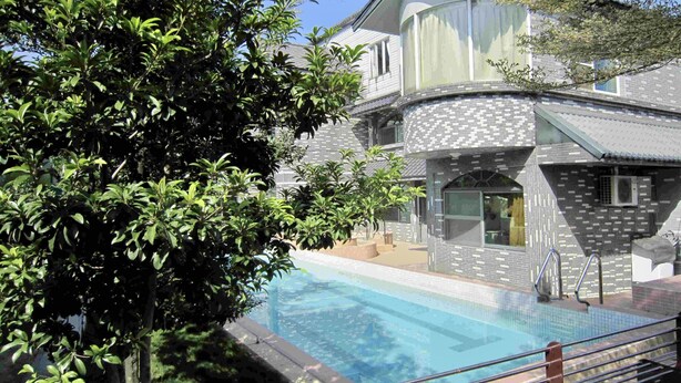 A modern building with a swimming pool, surrounded by lush greenery. - Treehouse (Yanpu)