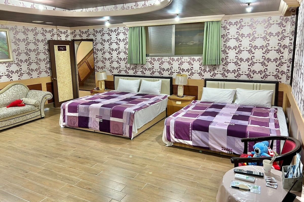 Habitación de hotel con dos camas, un sofá, piso de madera y un espejo.