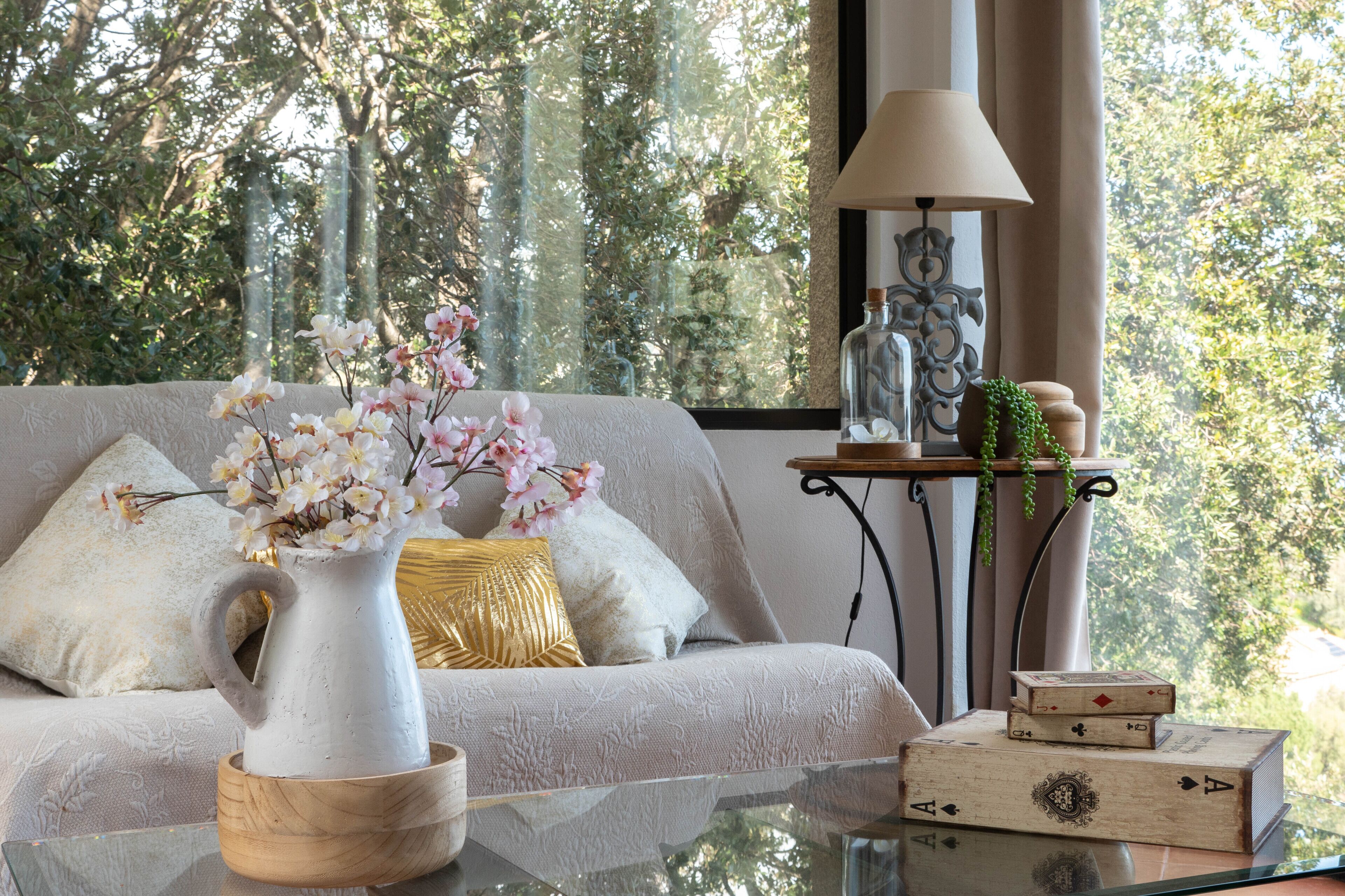 Une pièce comprenant un canapé, un vase avec des fleurs, une lampe et des boîtes décoratives.