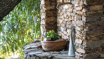 A stone wall with a potted plant and a metal sculpture.