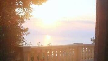 Sonnenuntergangblick von einem Balkon mit Steinbrüstung und Pflanzen in Töpfen.
