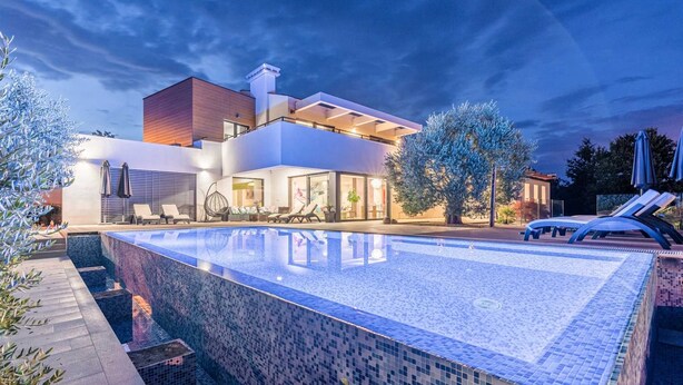 A modern hotel with a large outdoor swimming pool, lounge area, and a well-lit building. - Beautiful modern 4-BR villa for 8 with pool in Istria (Pican)