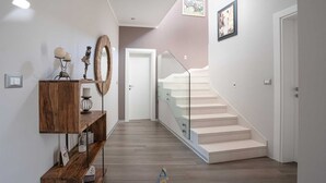 A modern interior with a wooden console table, a mirror, and a staircase with glass railings. - Beautiful modern 4-BR villa for 8 with pool in Istria (Pican)