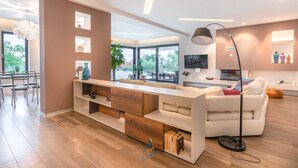 A modern living room with a sofa, a coffee table, and a TV. There is a dining area with chairs and a table. - Beautiful modern 4-BR villa for 8 with pool in Istria (Pican)