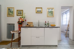 A kitchen with white cabinets, a marble countertop, a sink, and framed pictures on the wall.