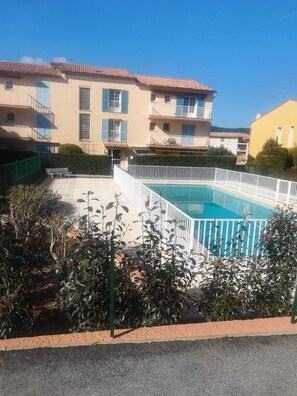 A residential building with a swimming pool surrounded by a white fence.