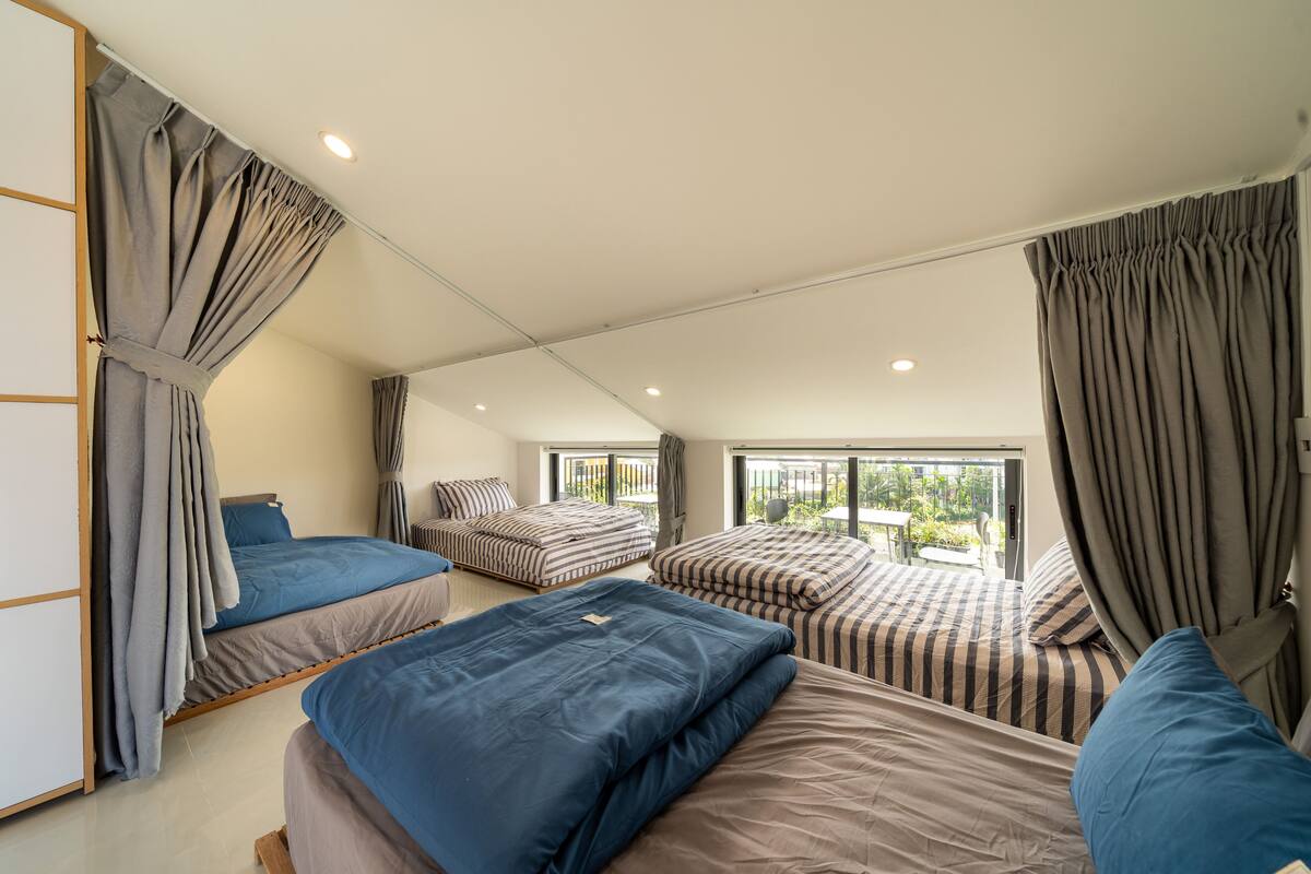 Ein Schlafzimmer mit zwei Betten, einem großen Fenster und Blick auf Grünfläche.