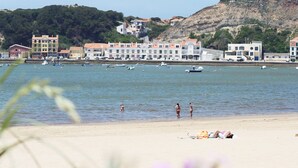 Un pueblo costero con edificios a lo largo del frente marítimo, barcos en el agua y gente en la playa.