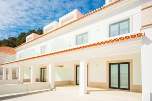 A modern two-story building with a covered patio area, large windows, and a flat roof. - Janelas da Baía - By SCH (São Martinho do Porto)