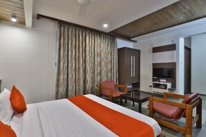 Ein modernes Hotelzimmer mit einem großen Bett, einem Fernseher, einem Holzsessel und einem Schreibtisch.