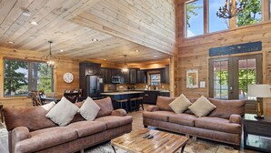 A spacious living area with leather sofas, a coffee table, and a kitchen in the background.