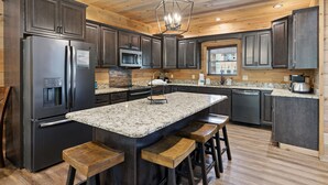 A modern kitchen with granite countertops, stainless steel appliances, and wooden bar stools.