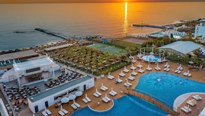 A resort with a swimming pool, sun loungers, and a view of the sunset over the sea. - Rubi Platinum Sign - All inclusive (Alanya)