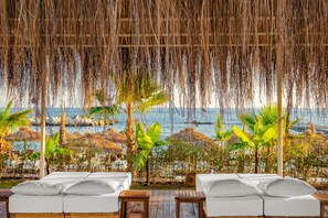 A beachside lounge with white cushioned seating and a view of the ocean. - Rubi Platinum Sign - All inclusive (Alanya)