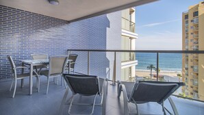 Un balcone con vista sulla spiaggia, un tavolo e sedie, e un muro rivestito di piastrelle blu.