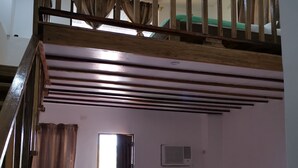 Une chambre avec deux lits, un escalier et un appareil de climatisation.