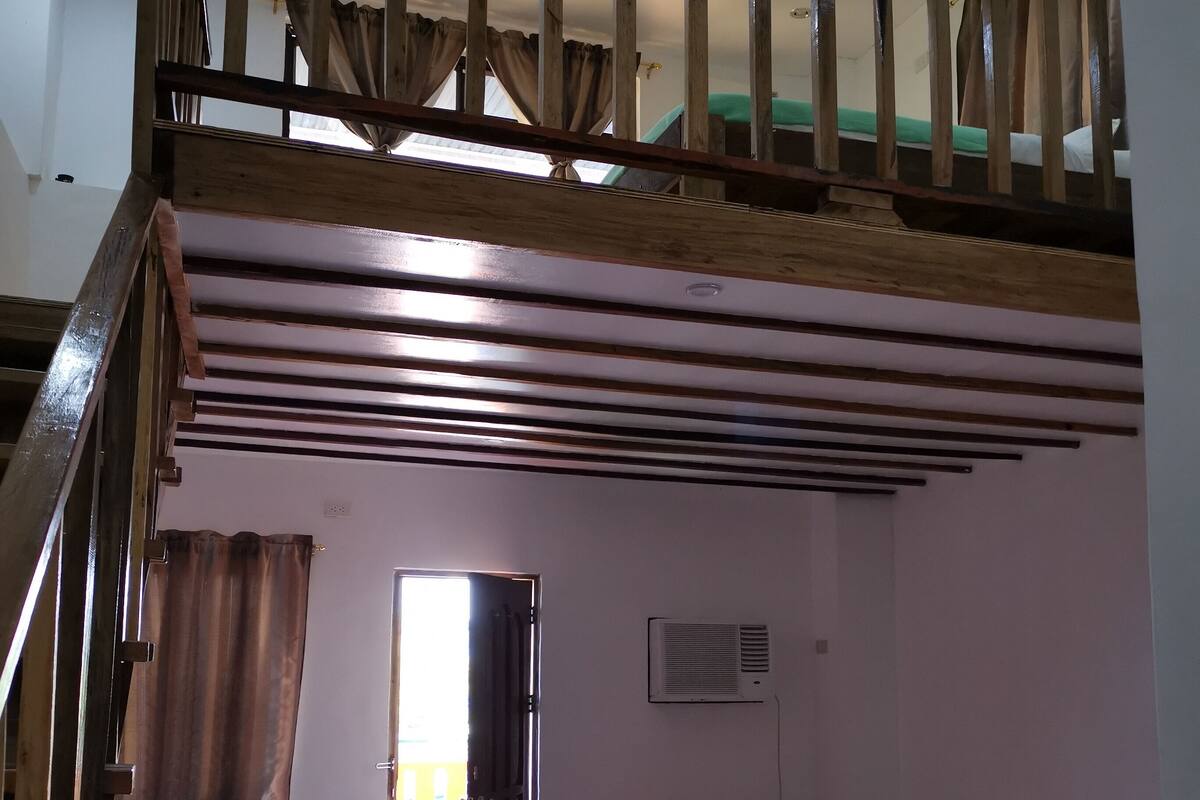 Ein Zimmer mit zwei Betten, einer Treppe und einer Klimaanlage.
