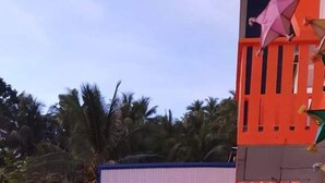 Un bâtiment doté d’une structure incurvée aux couleurs blanche et orange, d’un balcon orné de plantes et d’une enseigne indiquant un bureau où l’on peut obtenir des formulaires.
