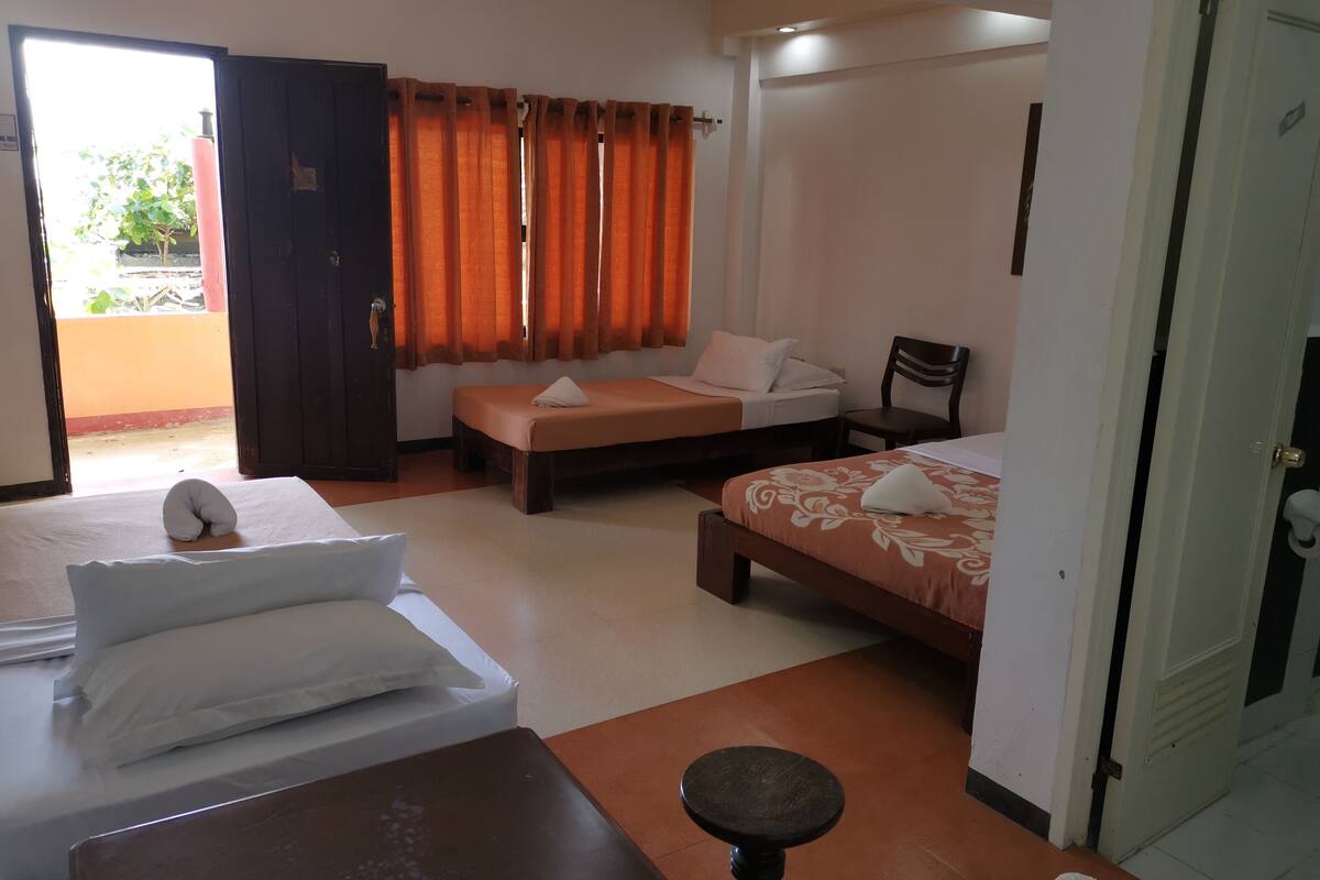 Ein Hotelzimmer mit zwei Betten, einem Holztisch, einem Stuhl und einer Tür.