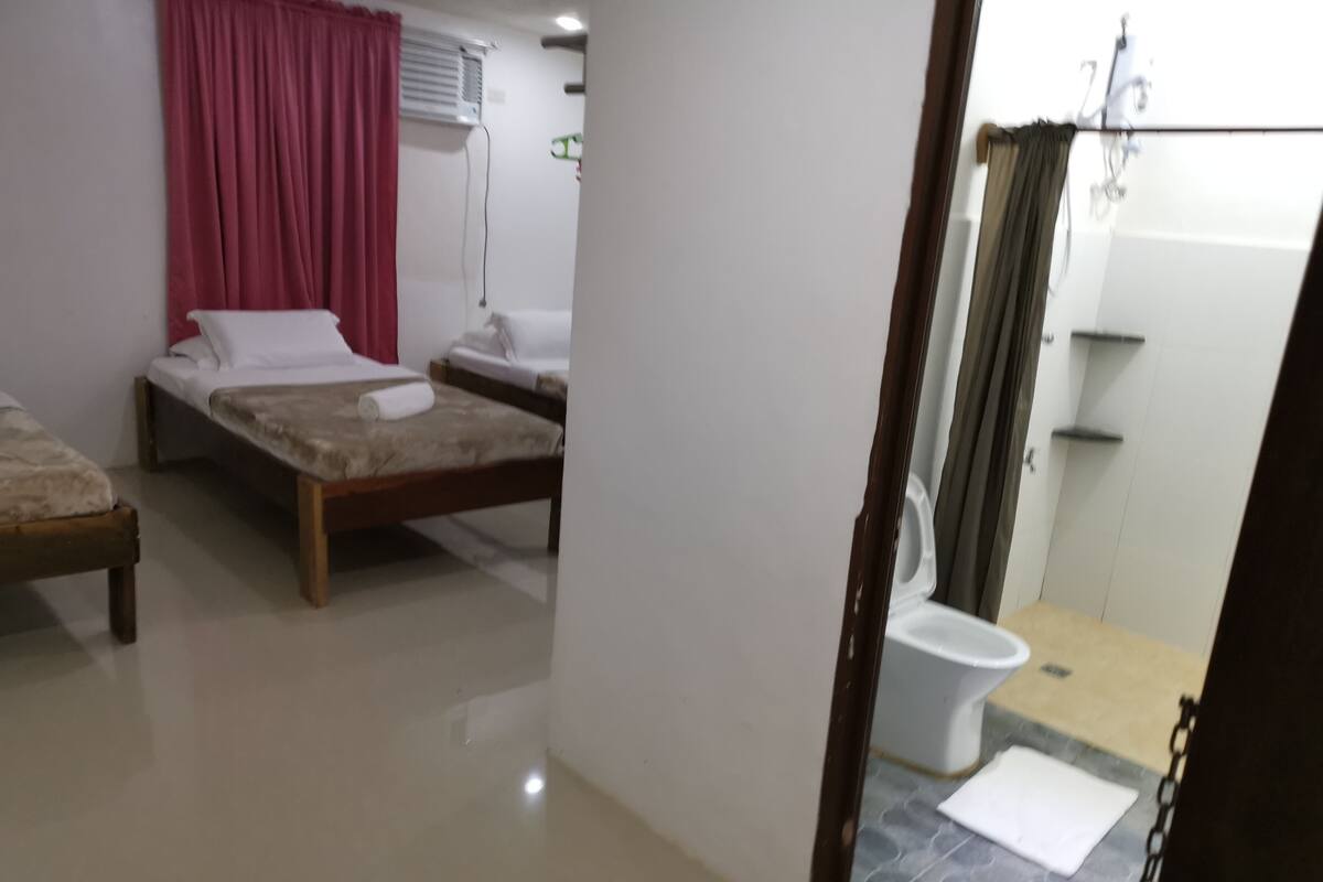 Ein Hotelzimmer mit zwei Betten, einem Badezimmer und einer kleinen Sitzecke.