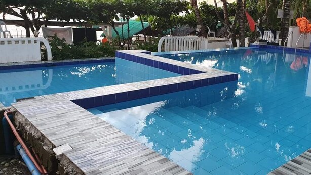 Une piscine aux carreaux bleus et une terrasse en bois.