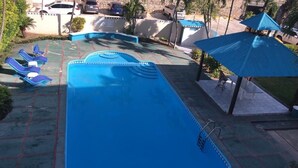 Una piscina con agua azul, rodeada de sillas de descanso y sombrillas.
