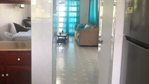 Una cocina con refrigerador, armarios de madera y piso de baldosas.