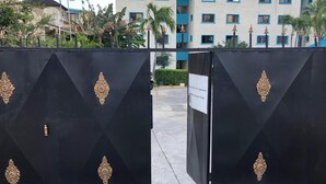 Una entrada protegida con detalles de metal decorativo, un letrero que indica propiedad privada y un edificio de fachada azul y blanca al fondo.
