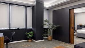 Una habitación de hotel moderna con un ventanal grande, un escritorio, una silla, una cama y dos plantas en macetas.