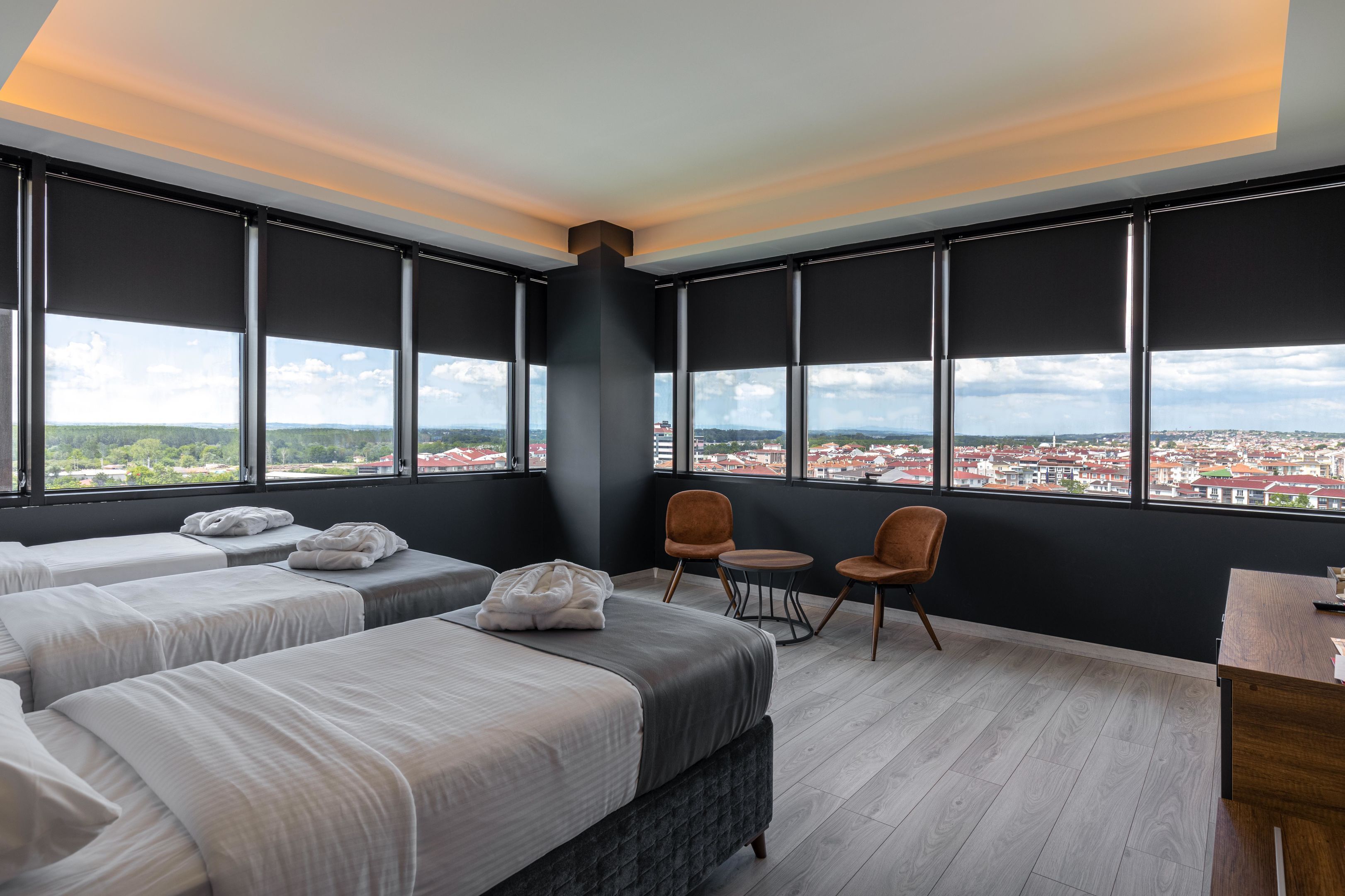 A hotel room with two beds, a desk, and a view of a cityscape.