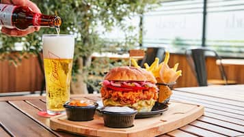 A meal with a chicken sandwich, fries, and a glass of beer on a wooden table.