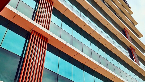 Ein modernes Hotel mit mehreren Etagen, großen Fenstern und einem auffälligen Farbkonzept in Rot und Beige.