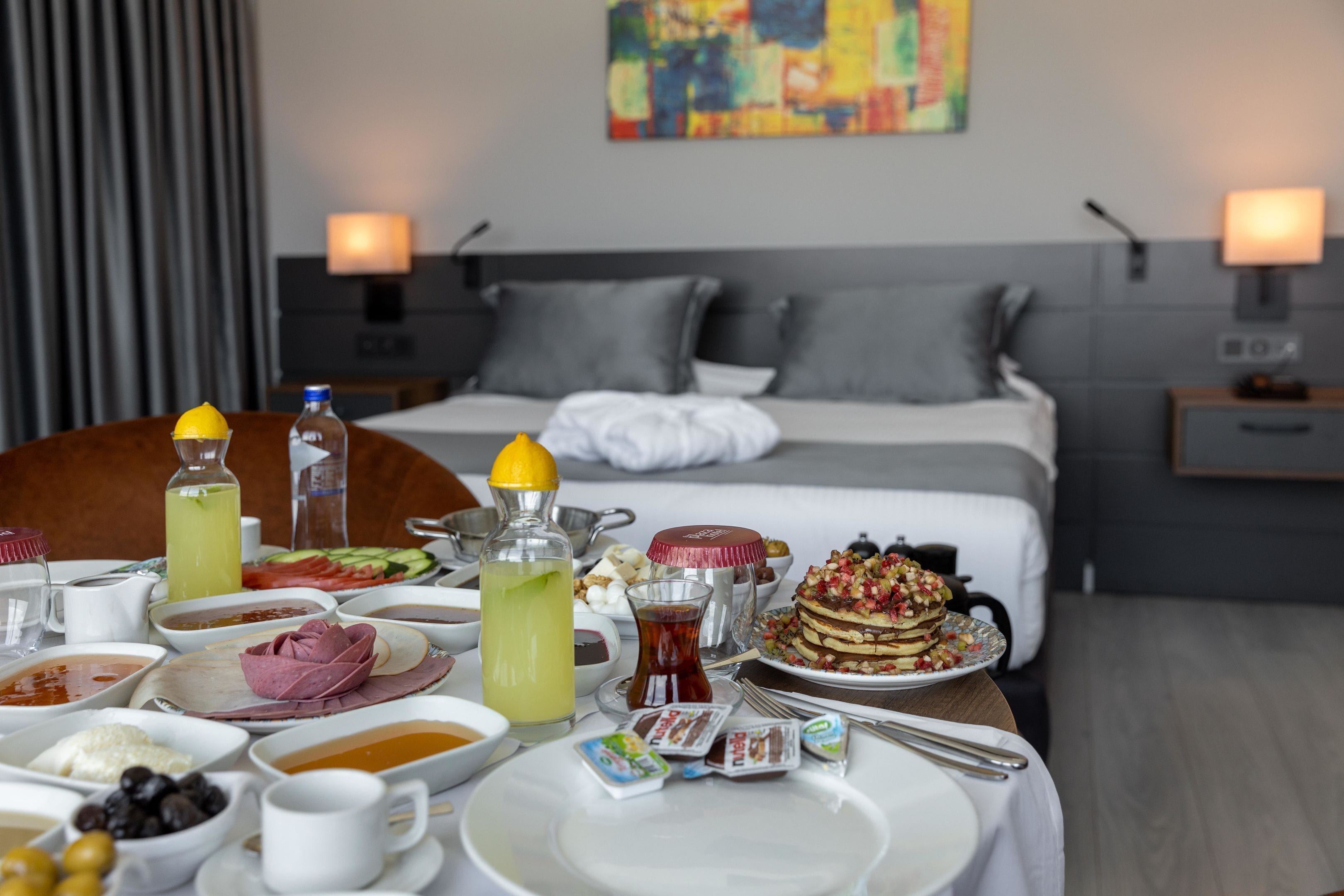 Una mesa de desayuno con diferentes platos, una cama y un cuadro en la pared.
