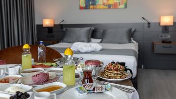 Una mesa de desayuno con diferentes platos, una cama y un cuadro en la pared.