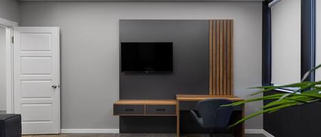 A modern room with a desk, chair, and a flat-screen TV mounted on the wall.