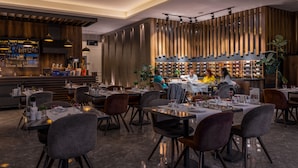 Ein modernes Restaurant mit Barbereich, Holzvertäfelung und verschiedenen Sitzmöglichkeiten.