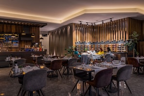 A modern restaurant with a bar area, wooden paneling, and a variety of seating options. - The Plaza Hotel Edirne (Edirne)