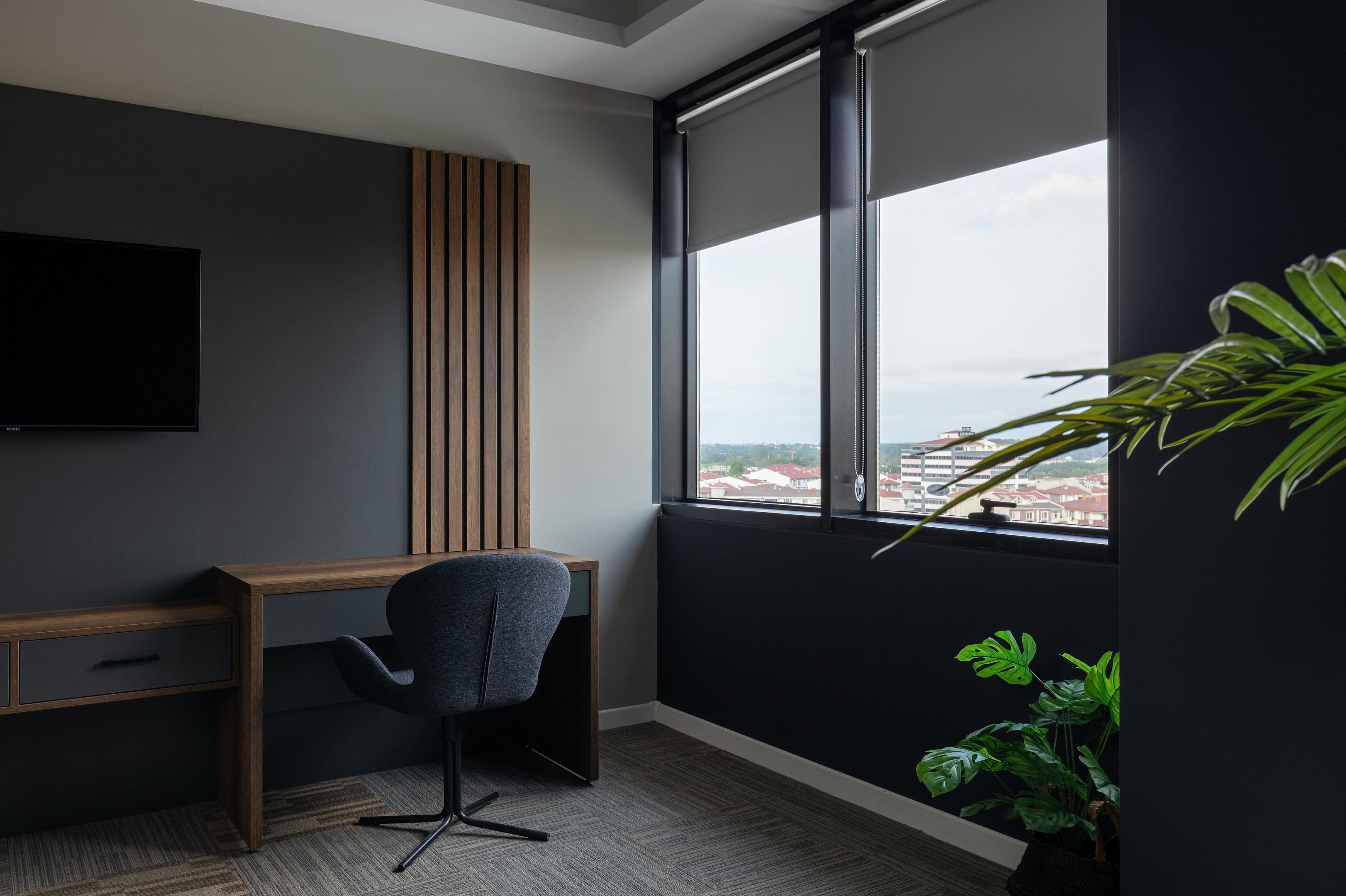 A modern office space with a desk, chair, and a large window offering a city view.