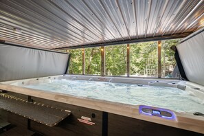 A hot tub with a wooden bench, a control panel, and a view of trees through large windows. - Emory House 8 Bedroom Cabin by RedAwning (Pigeon Forge)