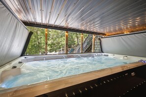 A hot tub with a view of a forest through a large window. - Emory House 8 Bedroom Cabin by RedAwning (Pigeon Forge)