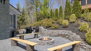 A stone fire pit with benches, surrounded by a gravel area and a stone wall. - Emory House 8 Bedroom Cabin by RedAwning (Pigeon Forge)