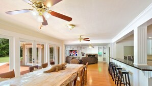 Una cocina amplia con una mesa de madera larga, taburetes de bar y ventiladores de techo.