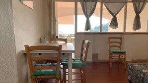 A room with a dining table and chairs, a bed with a floral bedspread, and a window with curtains. - Tuscany Hill / Sea Castagneto Carducci (Castagneto Carducci)