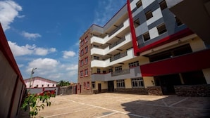 Un edificio de varios pisos con un patio interior, que presenta balcones y una combinación de paredes exteriores rojas y blancas.