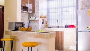 Una cocina con encimera de mármol, armarios de madera, microondas y refrigerador.
